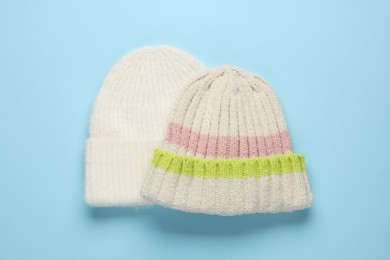 Photo of Warm woolen hats on light blue background, top view