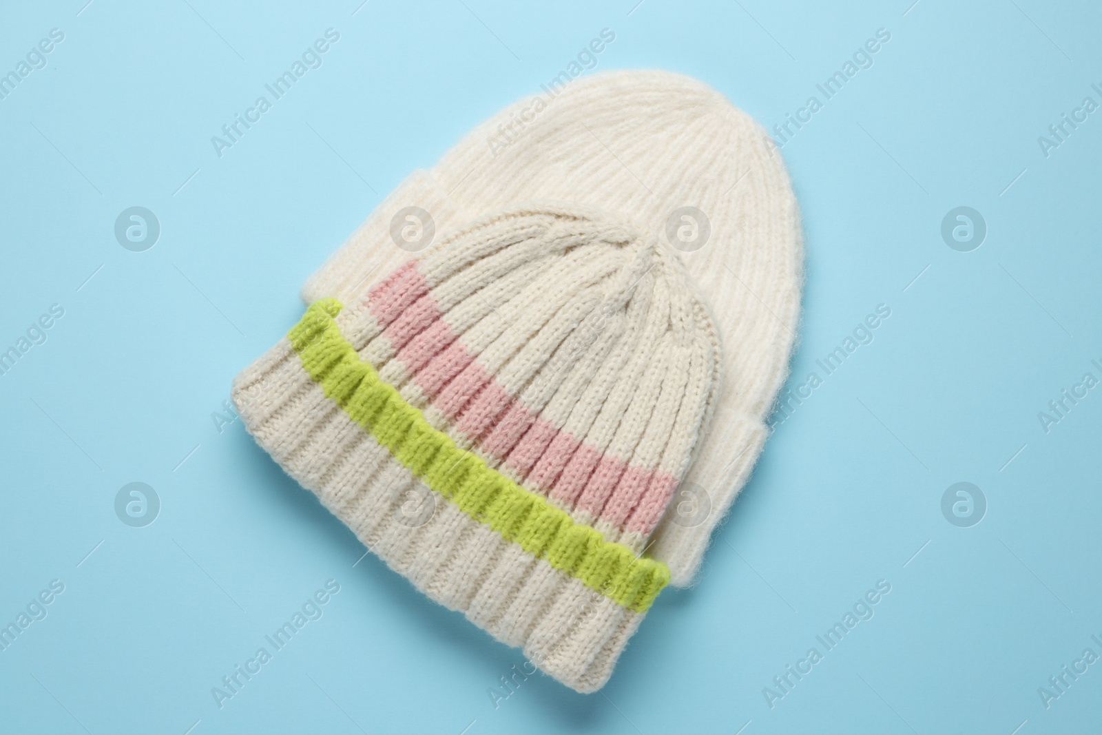 Photo of Warm woolen hats on light blue background, top view