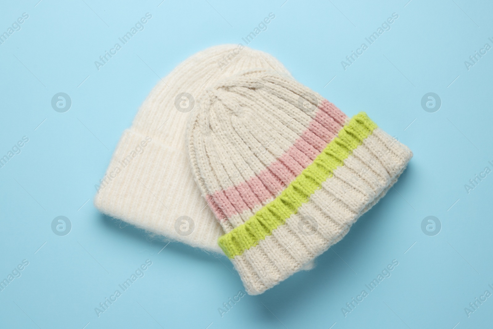 Photo of Warm woolen hats on light blue background, top view