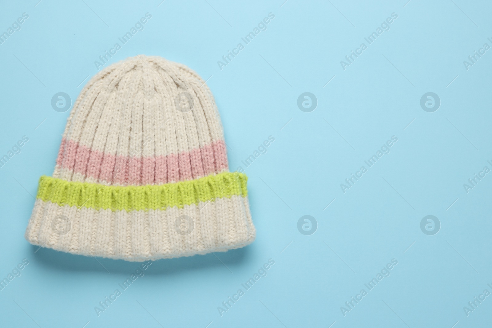 Photo of Warm woolen hat on light blue background, top view. Space for text