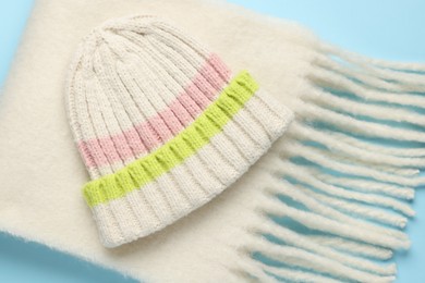 Photo of Warm woolen hat and scarf on light blue background, closeup