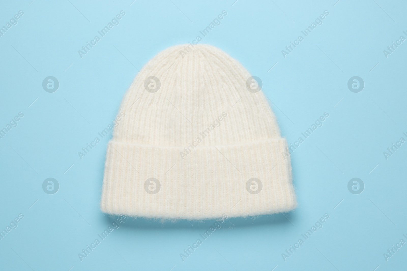 Photo of Warm woolen hat on light blue background, top view