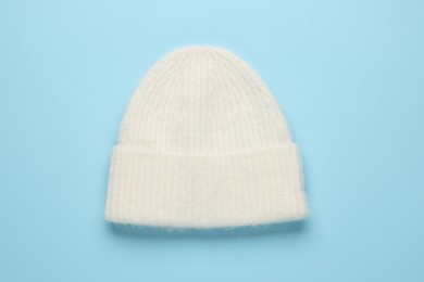 Photo of Warm woolen hat on light blue background, top view