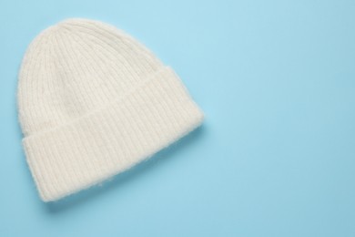 Photo of Warm woolen hat on light blue background, top view. Space for text