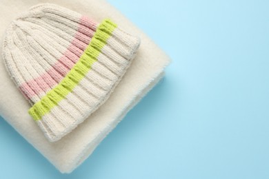 Photo of Warm woolen hat and scarf on light blue background, top view. Space for text