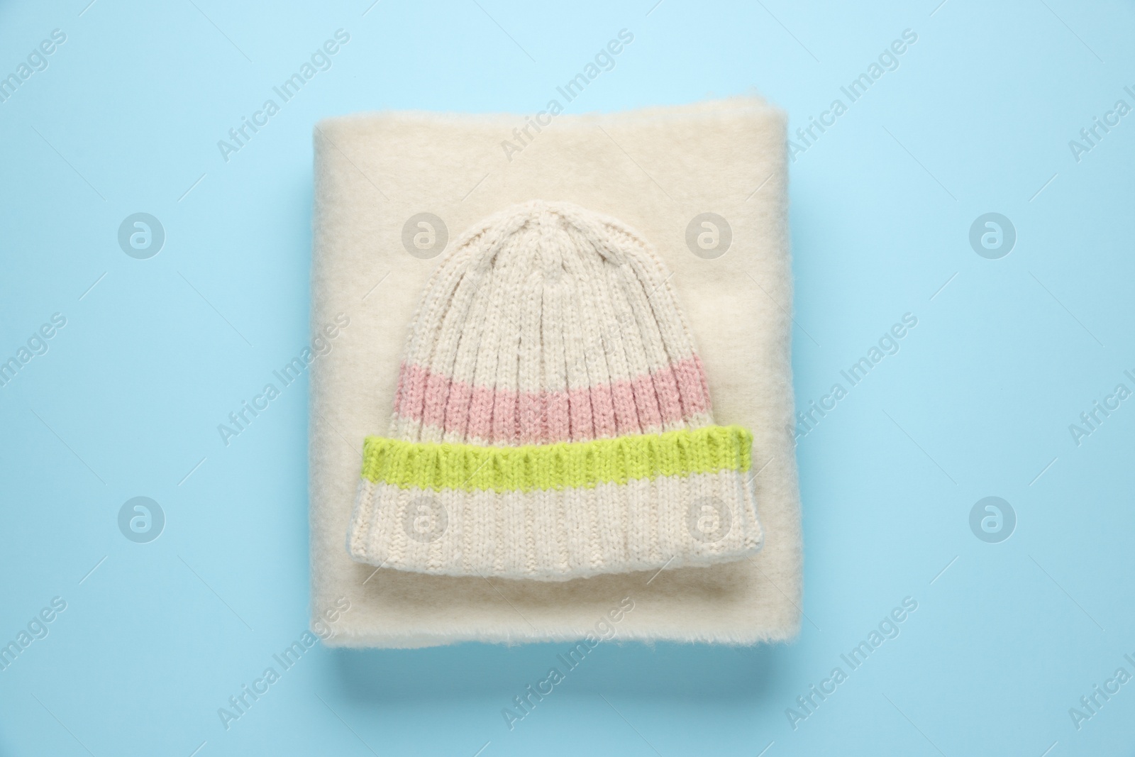 Photo of Warm woolen hat and scarf on light blue background, top view