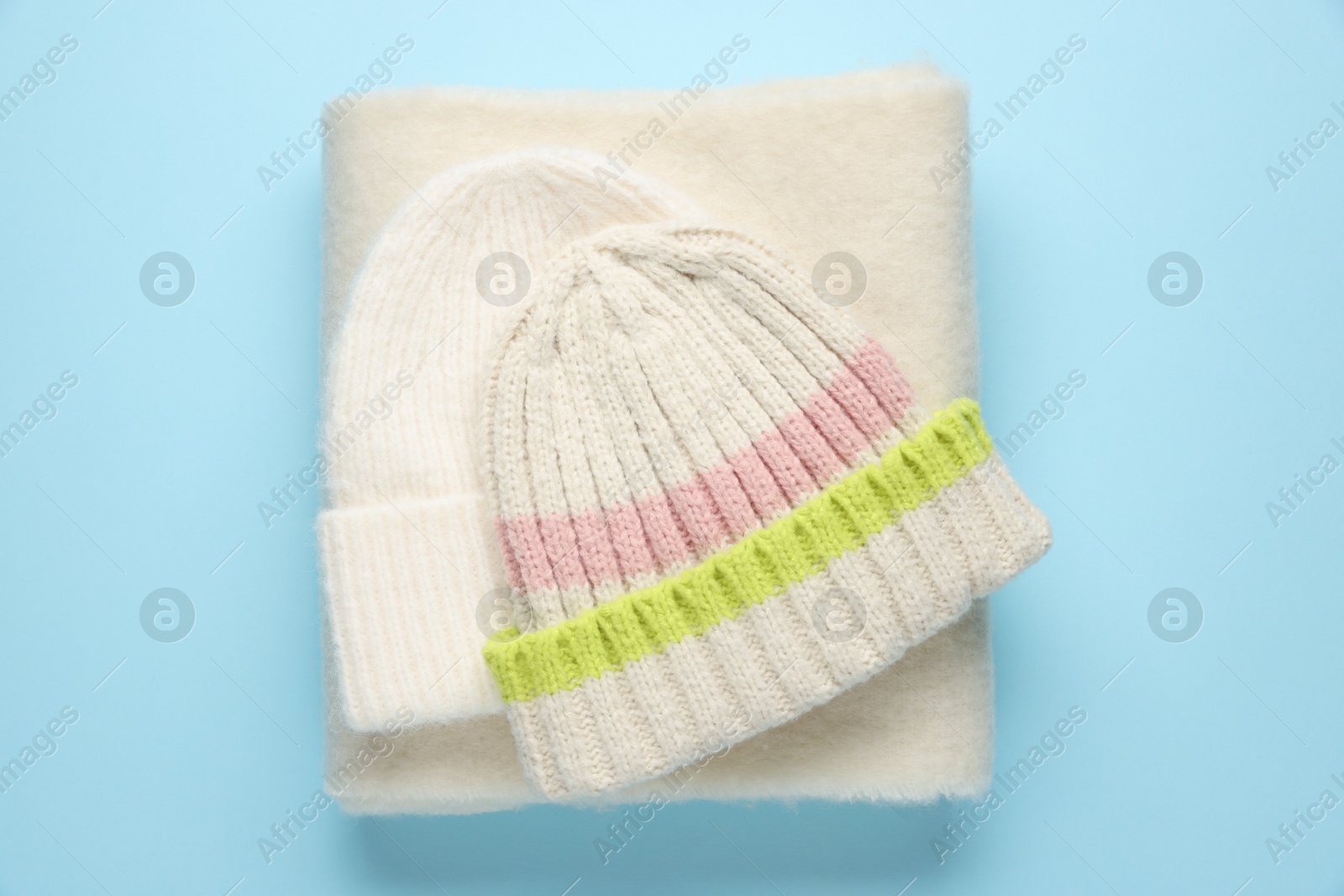 Photo of Warm woolen hat and scarf on light blue background, top view