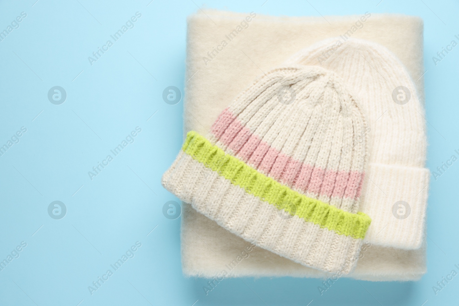 Photo of Warm woolen hat and scarf on light blue background, top view