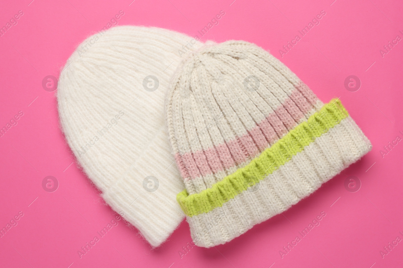 Photo of Warm woolen hats on pink background, top view