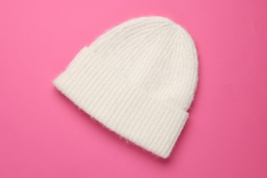 Photo of Warm woolen hat on pink background, top view