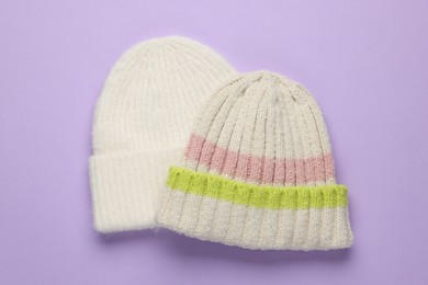 Photo of Warm woolen hats on lilac background, top view