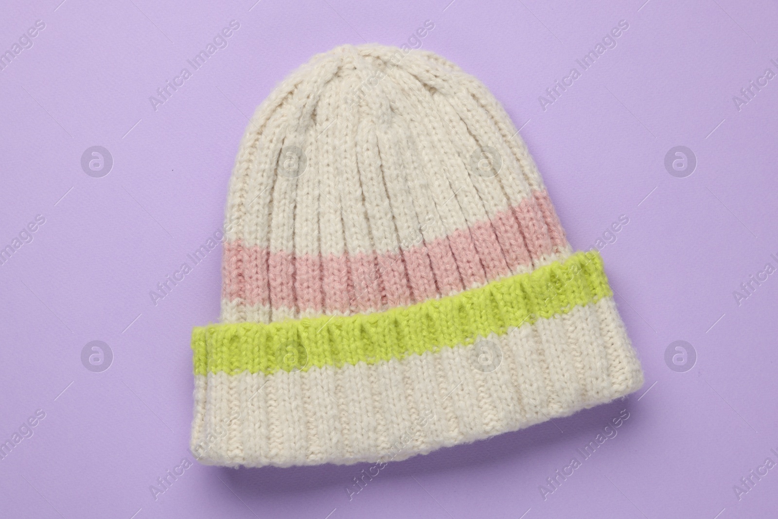 Photo of Warm woolen hat on lilac background, top view