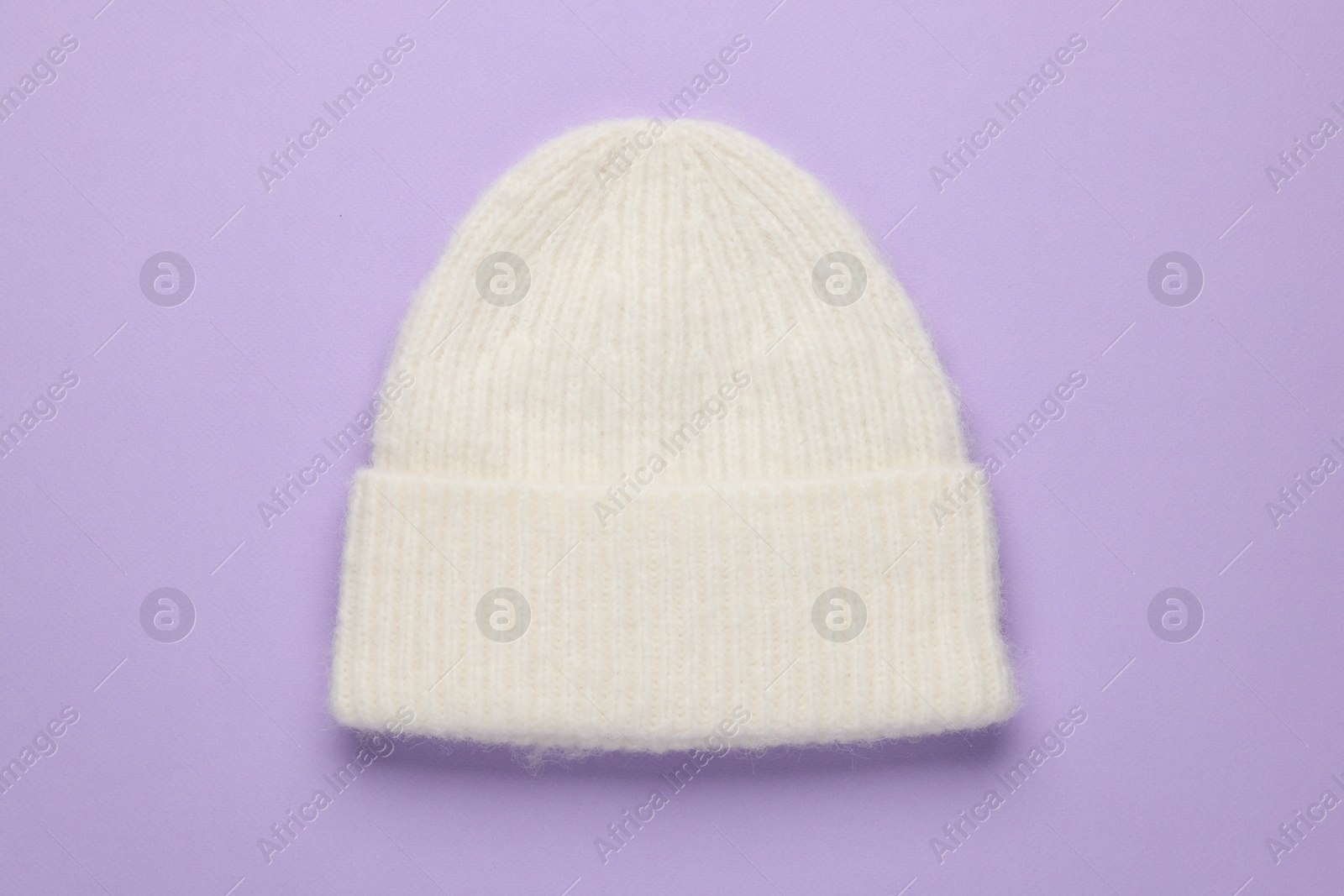 Photo of Warm woolen hat on lilac background, top view