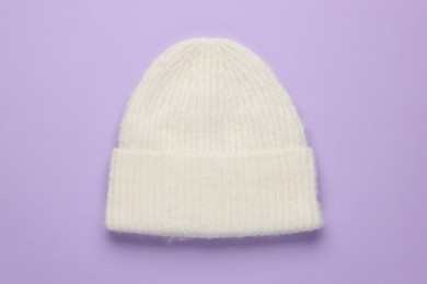 Photo of Warm woolen hat on lilac background, top view