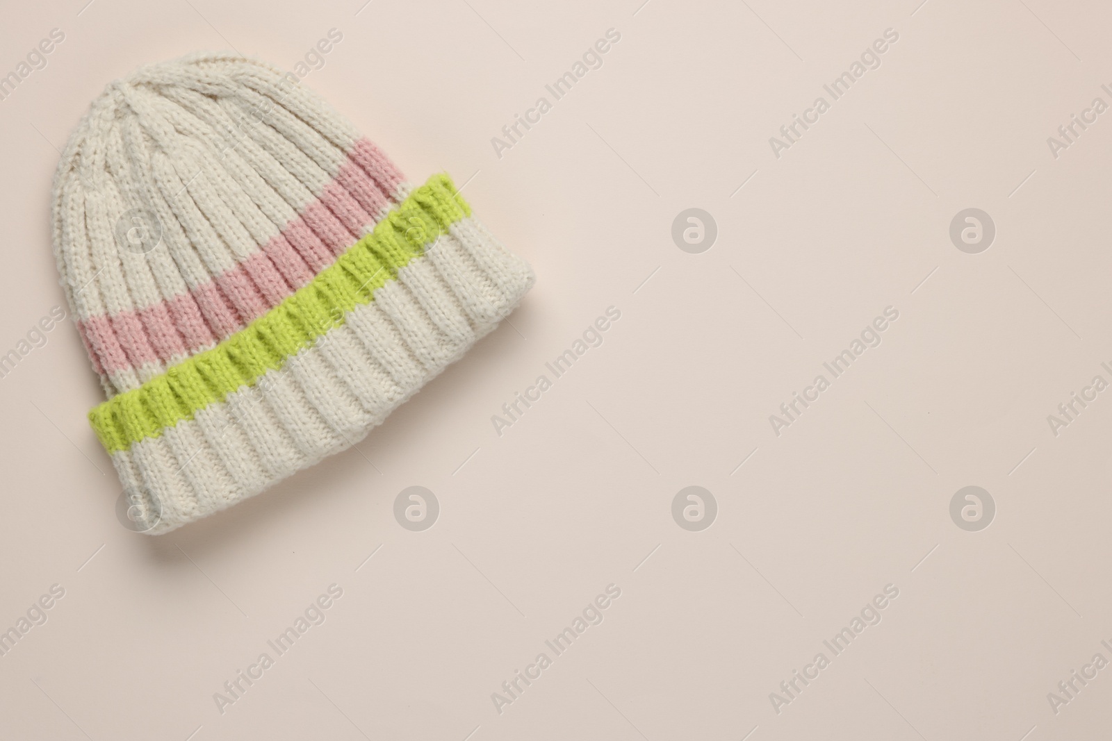 Photo of Warm woolen hat on beige background, top view. Space for text