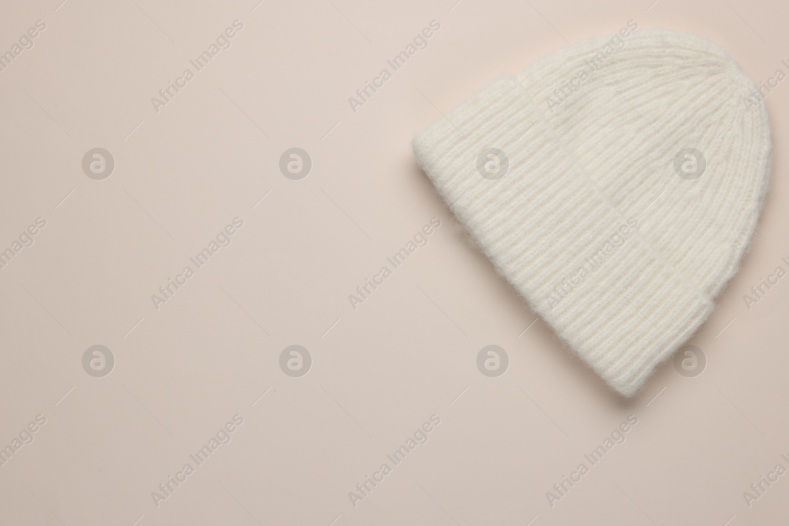 Photo of Warm woolen hat on beige background, top view. Space for text