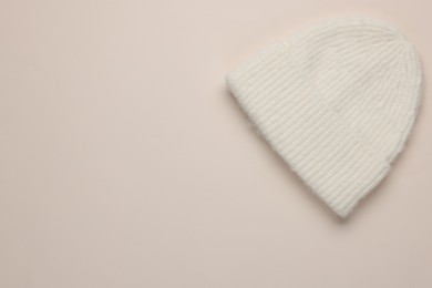 Photo of Warm woolen hat on beige background, top view. Space for text