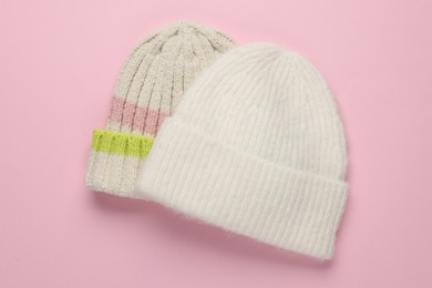 Photo of Warm woolen hats on light pink background, top view