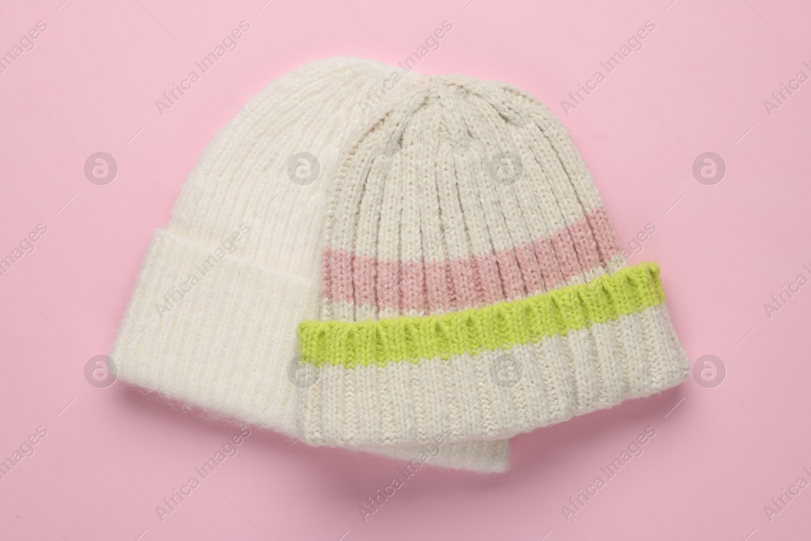 Photo of Warm woolen hats on light pink background, top view