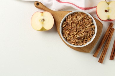 Photo of Delicious apple crisp in bowl, fresh fruits and cinnamon sticks on white table, flat lay. Space for text