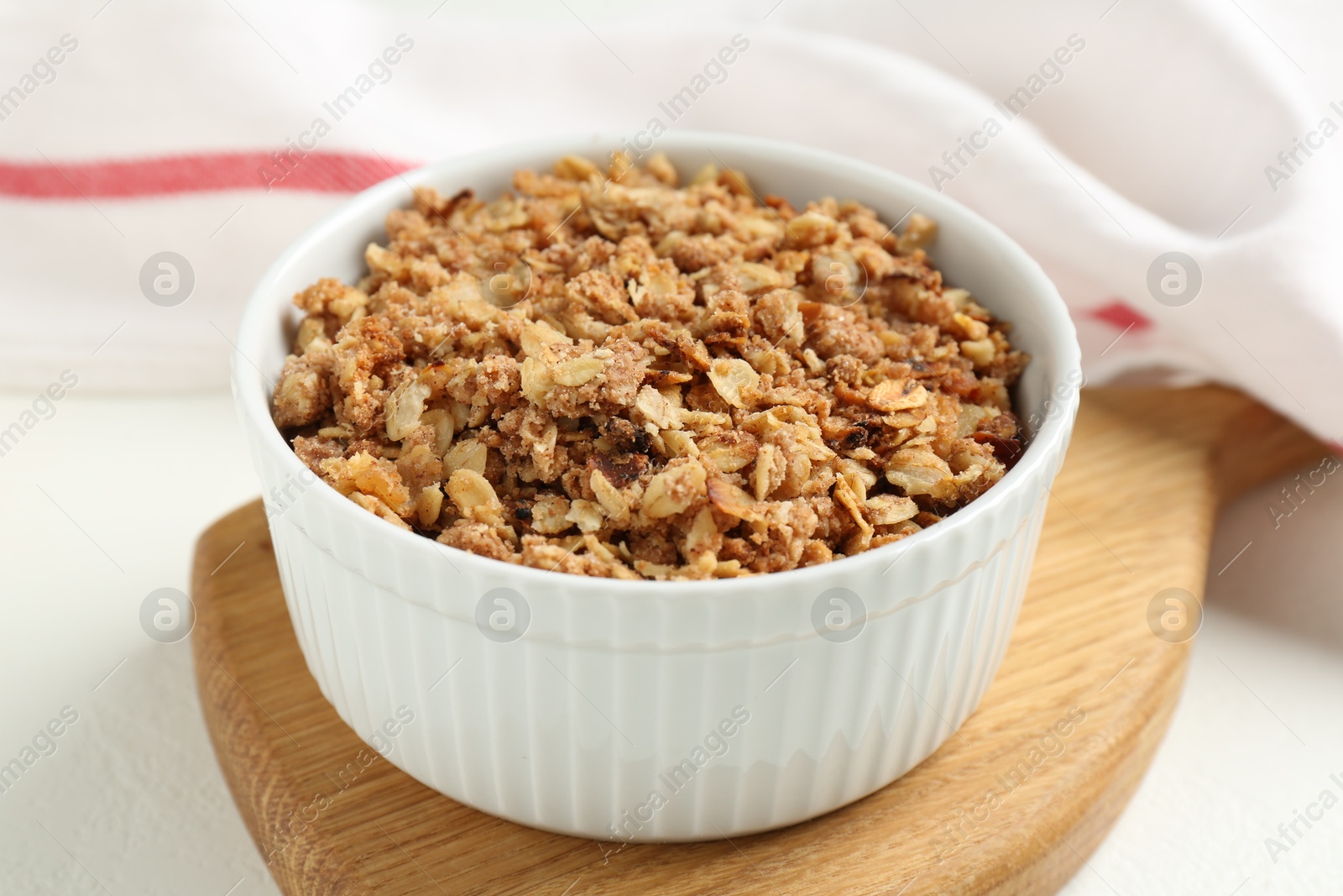 Photo of Delicious apple crisp in bowl on white table, closeup