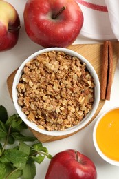 Photo of Delicious apple crisp in bowl, fresh fruits, mint, honey and cinnamon stick on white table, flat lay