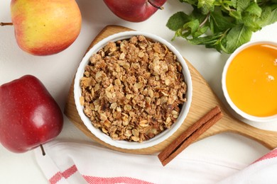 Photo of Delicious apple crisp in bowl, fresh fruits, mint, honey and cinnamon stick on white table, flat lay