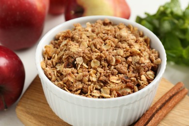 Photo of Delicious apple crisp in bowl, cinnamon, fresh fruits and mint on table, closeup