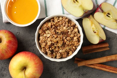 Photo of Delicious apple crisp in bowl, fresh fruits, cinnamon sticks and honey on grey table, flat lay