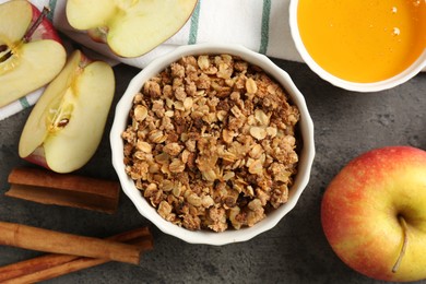 Photo of Delicious apple crisp in bowl, fresh fruits, cinnamon sticks and honey on grey table, flat lay