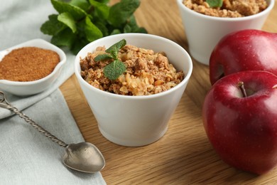 Delicious apple crisp, fresh fruits, cinnamon and mint on wooden table, closeup