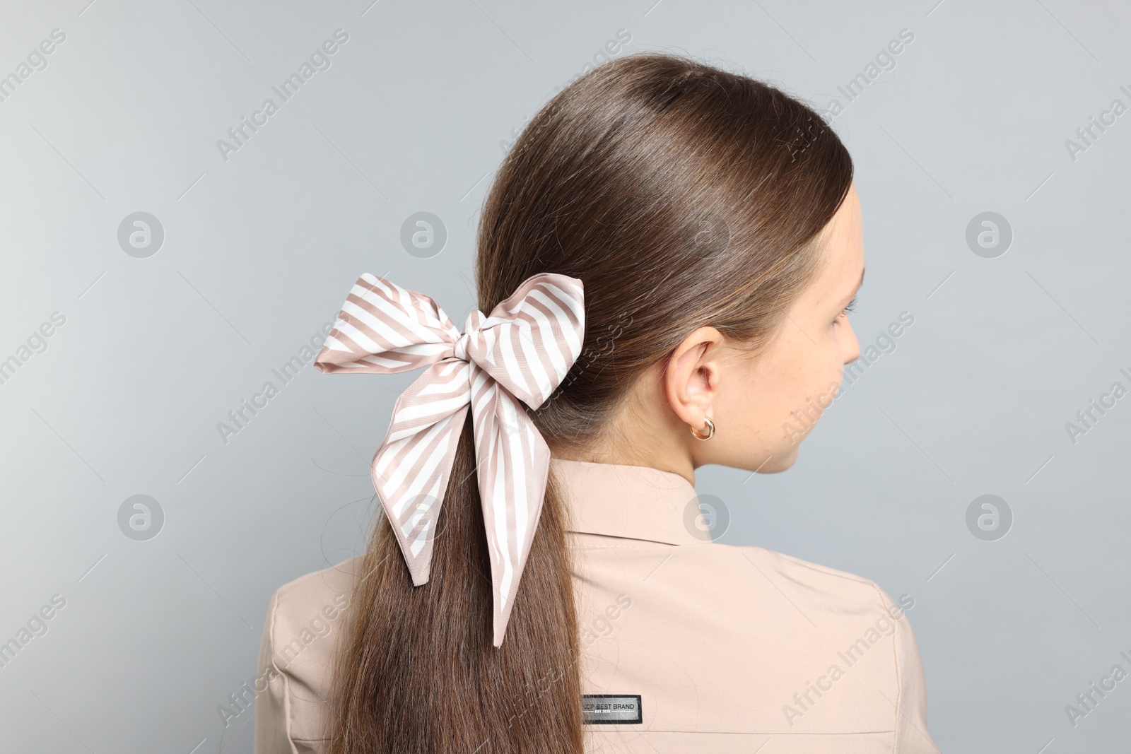 Photo of Teenage girl with stylish hair band on light grey background, back view