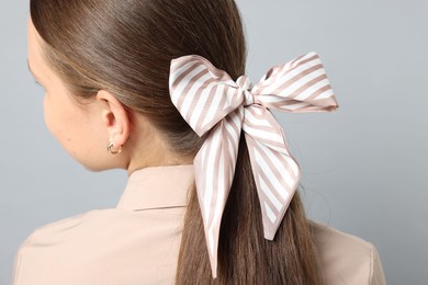 Photo of Teenage girl with stylish hair band on light grey background, back view