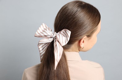 Photo of Teenage girl with stylish hair band on light grey background, back view