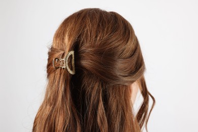 Teenage girl with stylish hair clip on white background, back view