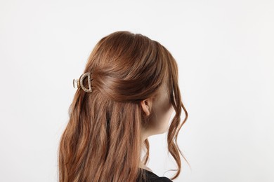 Photo of Teenage girl with stylish hair clip on white background, back view