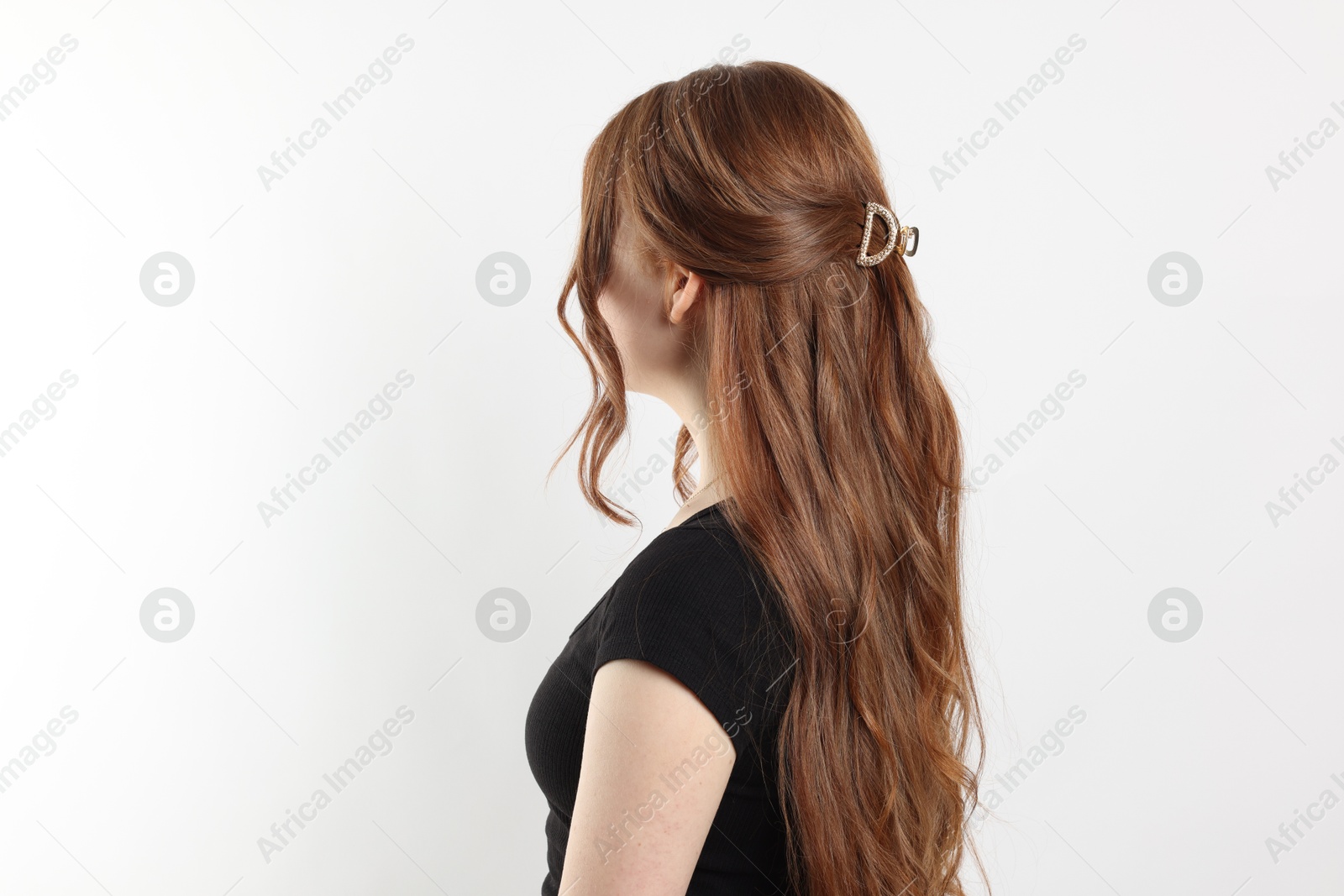 Photo of Teenage girl with stylish hair clip on white background, back view