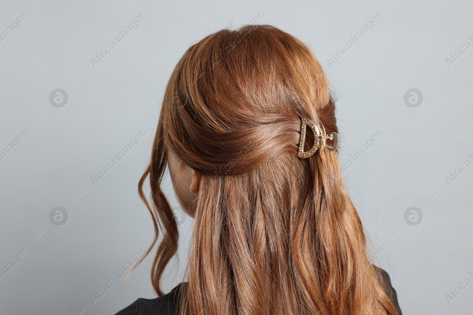 Photo of Teenage girl with stylish hair clip on light grey background, back view