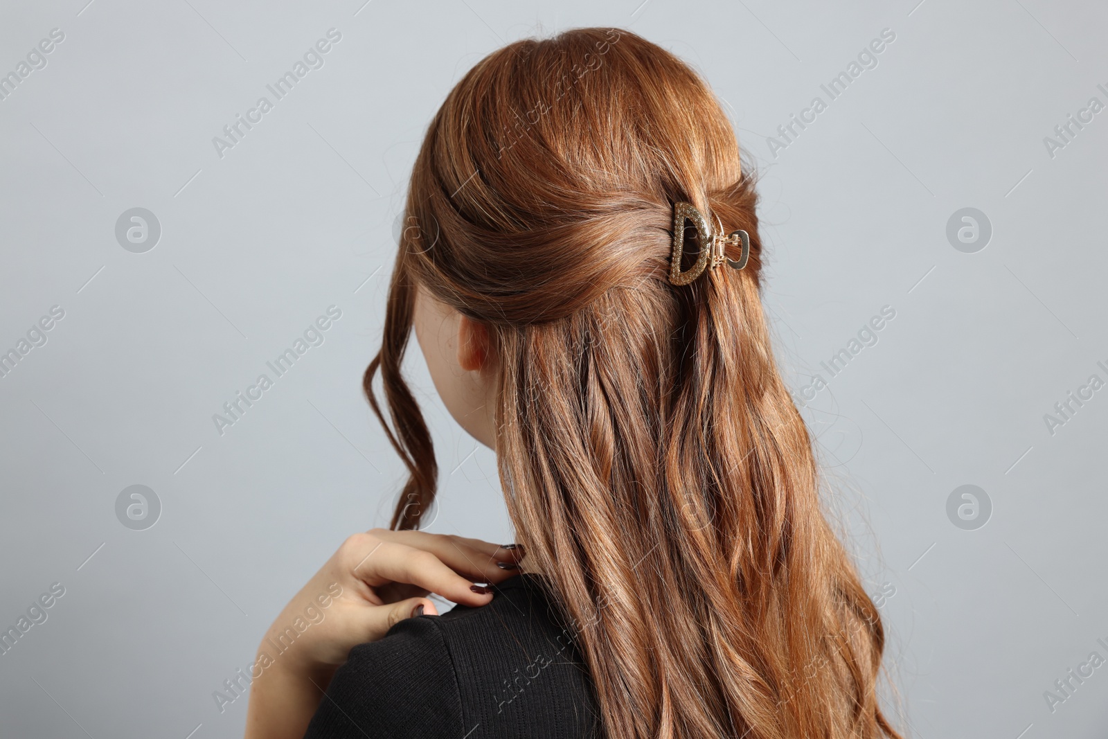 Photo of Teenage girl with stylish hair clip on light grey background, back view