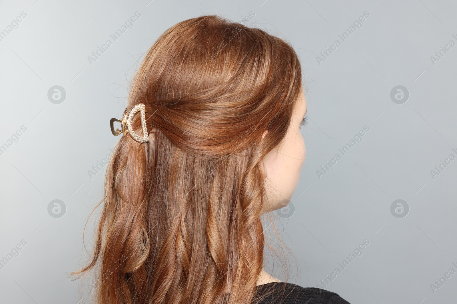 Photo of Teenage girl with stylish hair clip on light grey background, back view