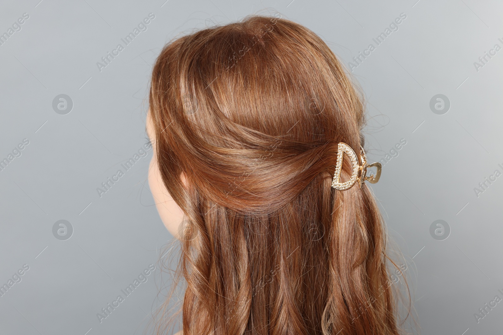 Photo of Teenage girl with stylish hair clip on light grey background, back view