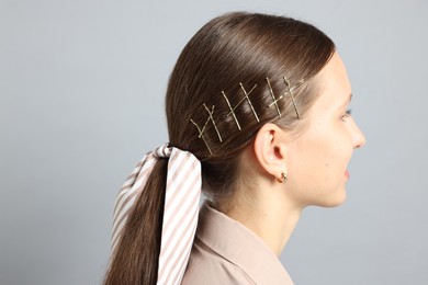 Teenage girl with stylish hair clips and bandana on light grey background