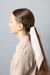 Photo of Teenage girl with stylish hair clips and bandana on light grey background