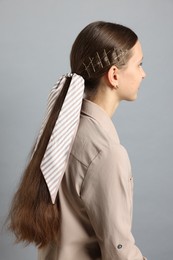 Photo of Teenage girl with stylish hair clips and bandana on light grey background