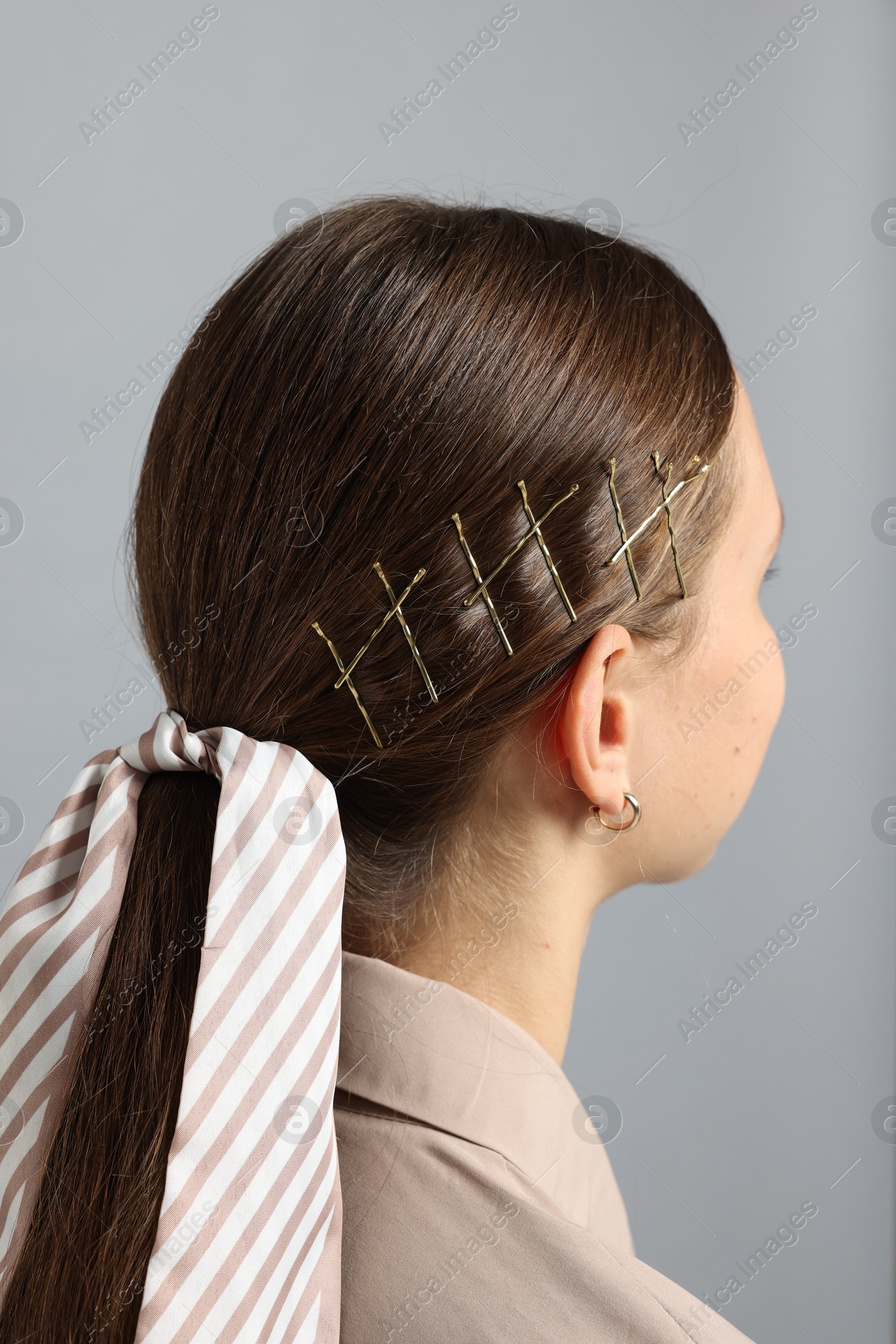 Photo of Teenage girl with stylish hair clips and bandana on light grey background, back view