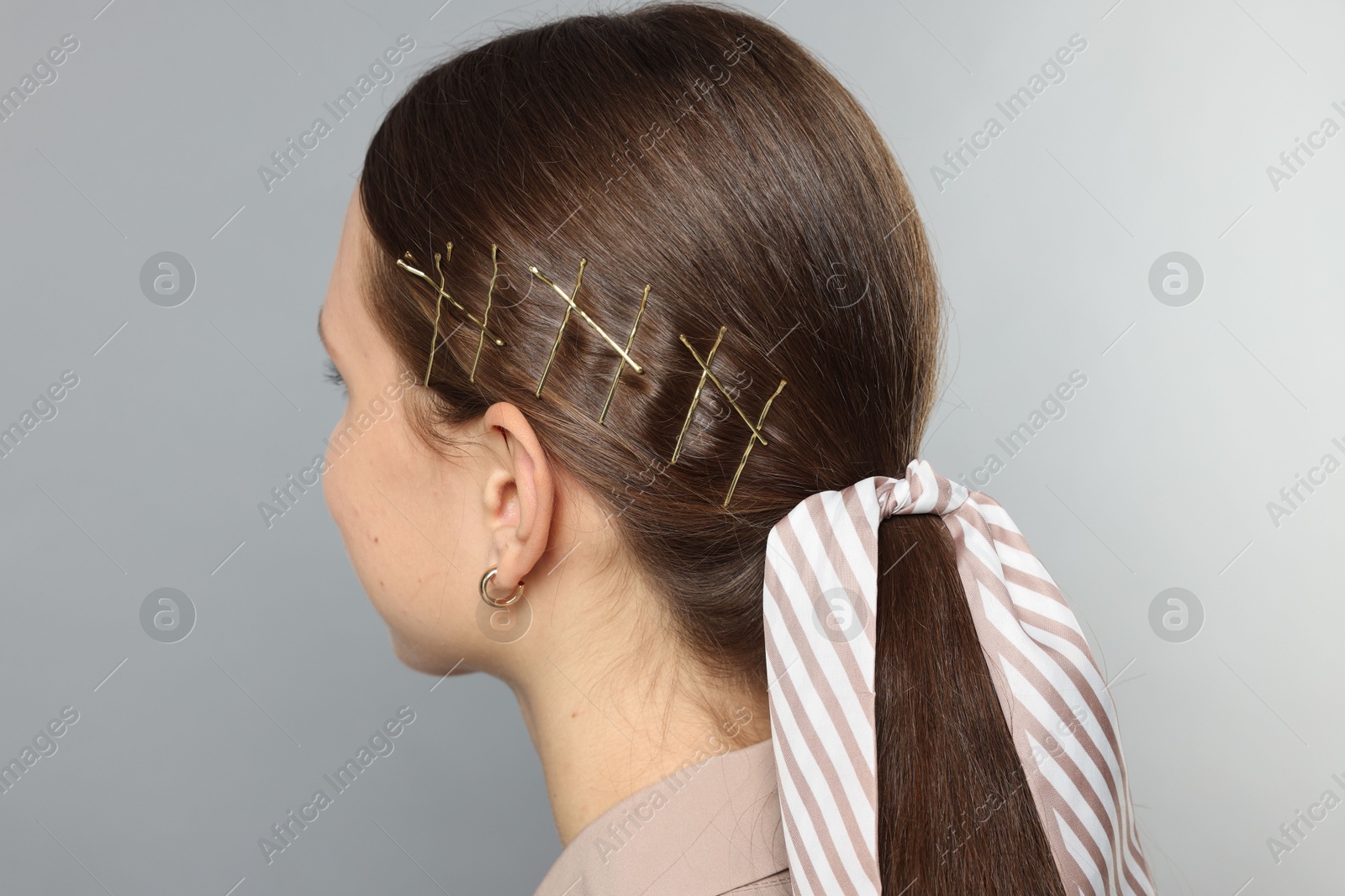 Photo of Teenage girl with stylish hair clips and bandana on light grey background, back view