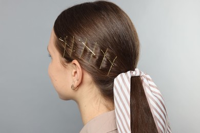 Photo of Teenage girl with stylish hair clips and bandana on light grey background, back view