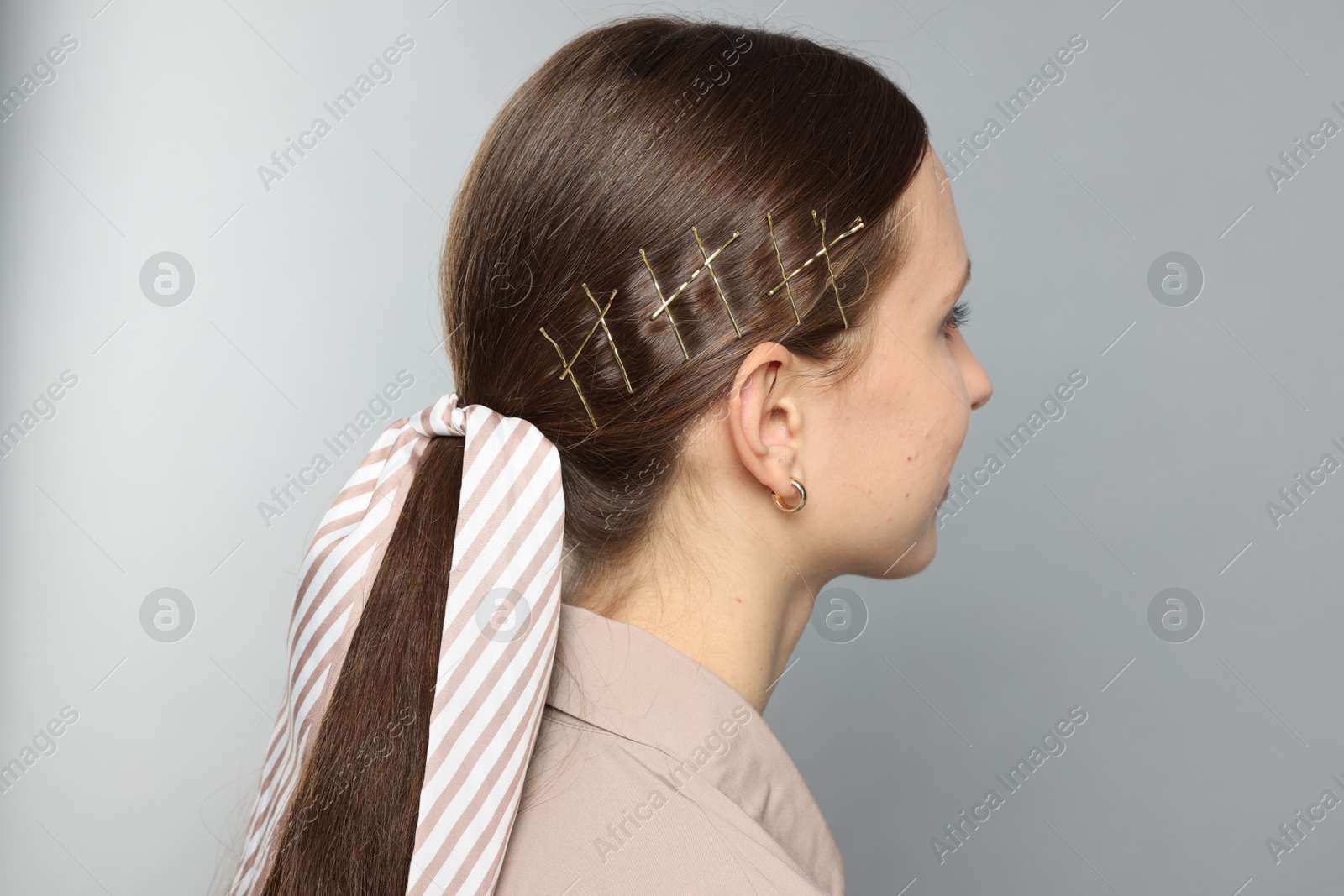 Photo of Teenage girl with stylish hair clips and bandana on light grey background, back view