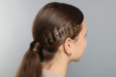 Photo of Teenage girl with stylish hair clips on light grey background, back view