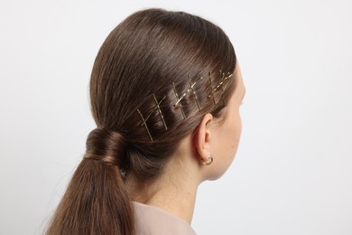 Teenage girl with stylish hair clips on white background, back view